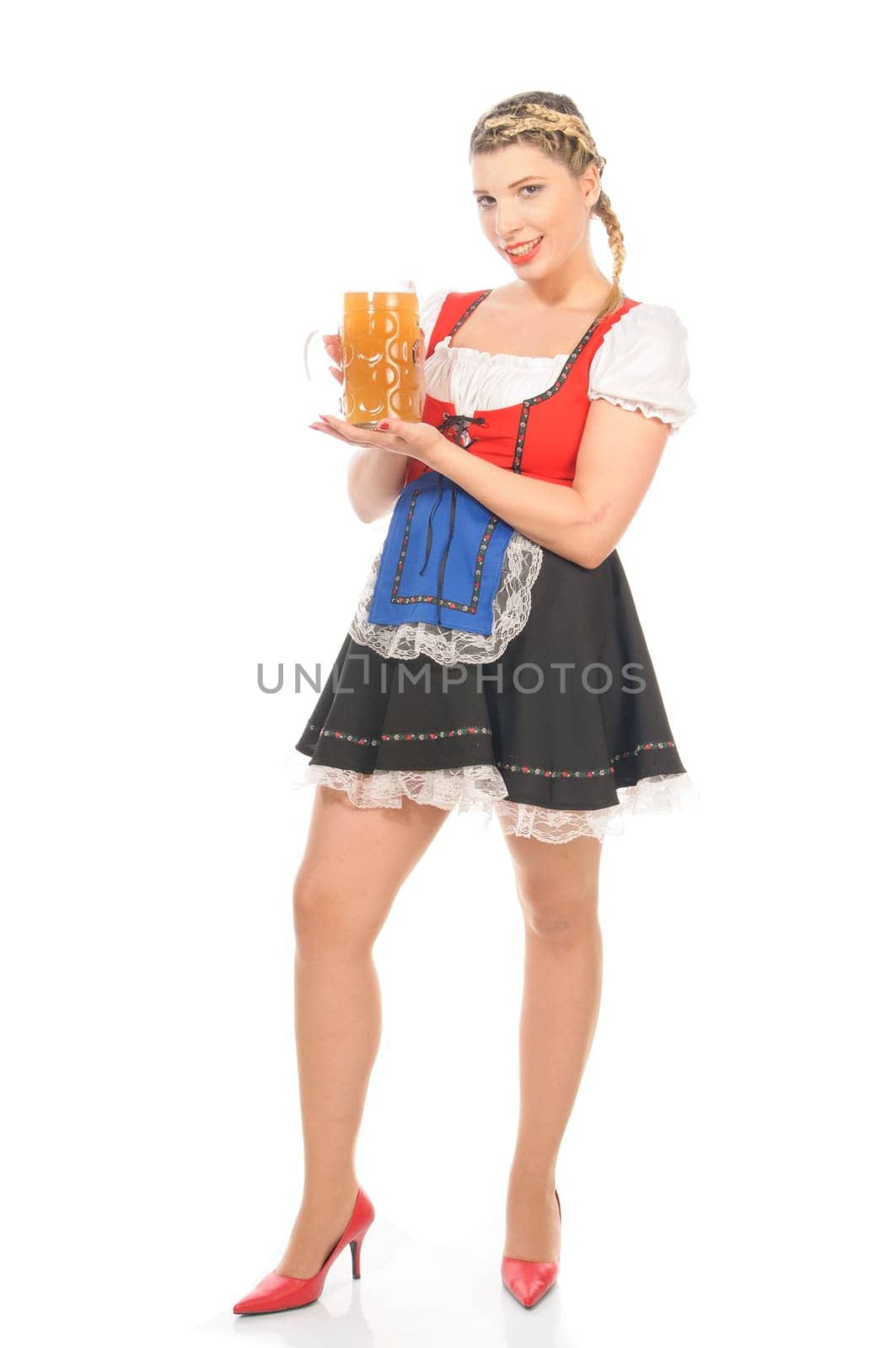 Young attractive woman with blond hair and braids wears a colorful dirdl dress and holds a mug of freshly tapped beer in her hand,exposed against a white background.