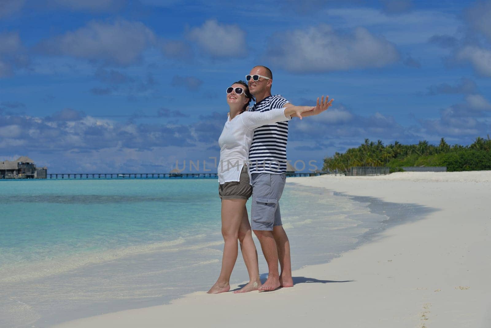 happy young couple have fun and relax at summer vacation on background maldives travel location and beautiful white sand beach