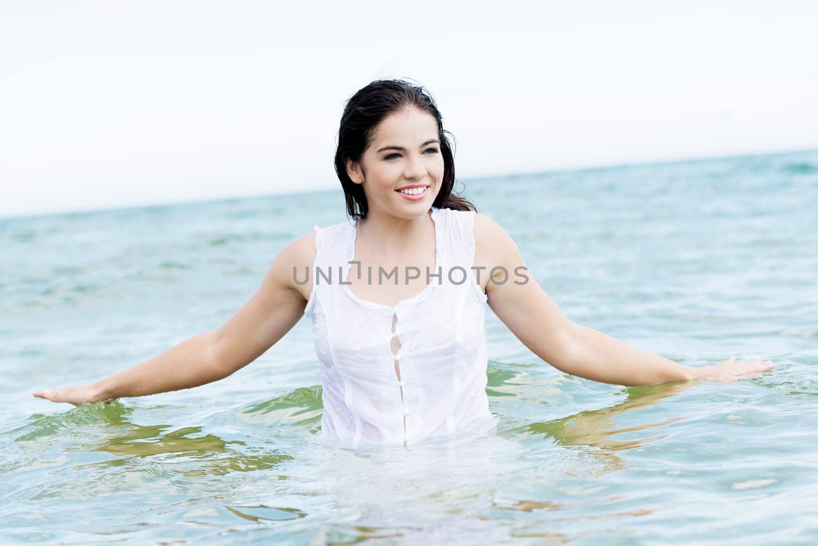 summer happy woman in water,wearing a white dress.