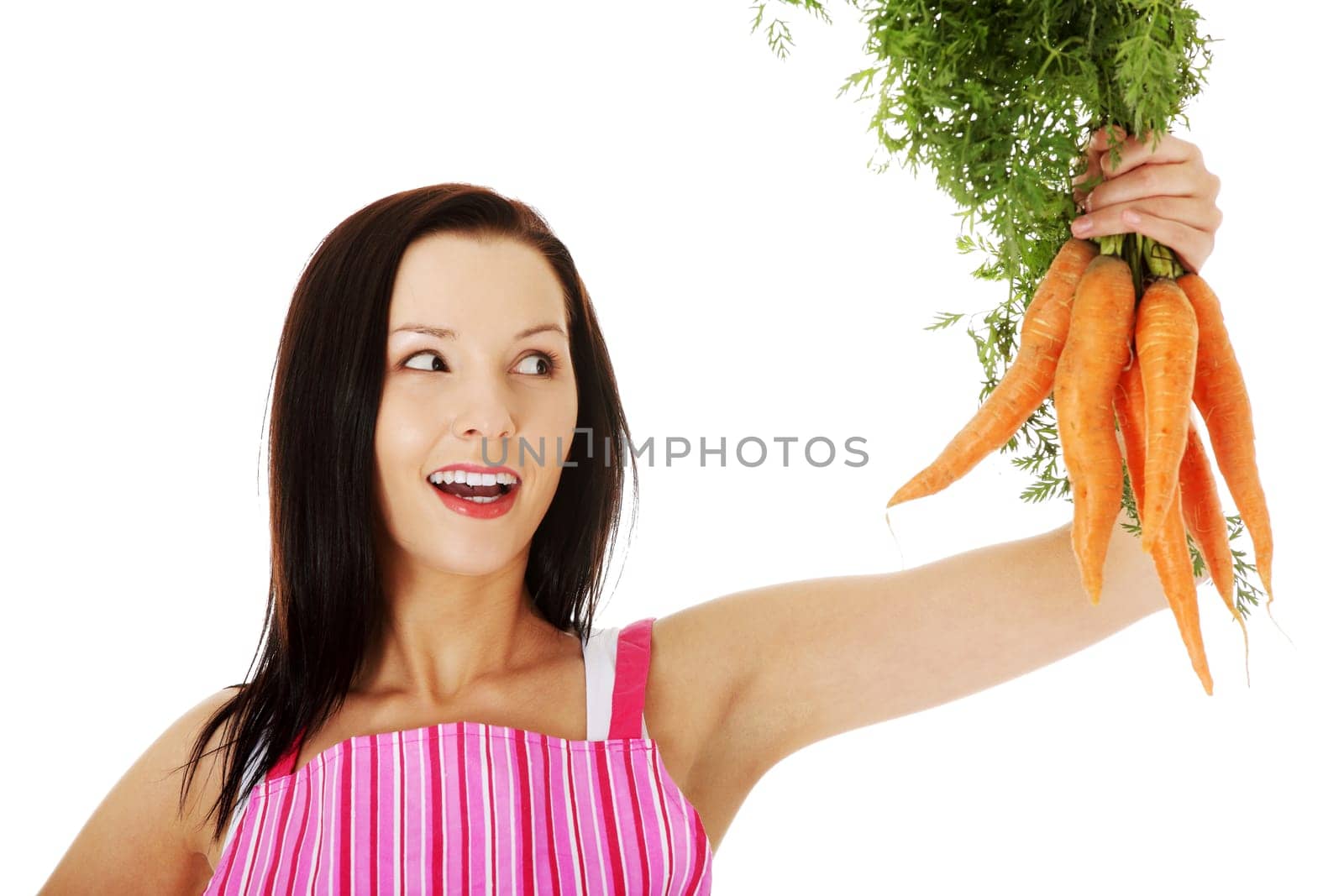 young woman in pink kitchen apron holding fresh carrots