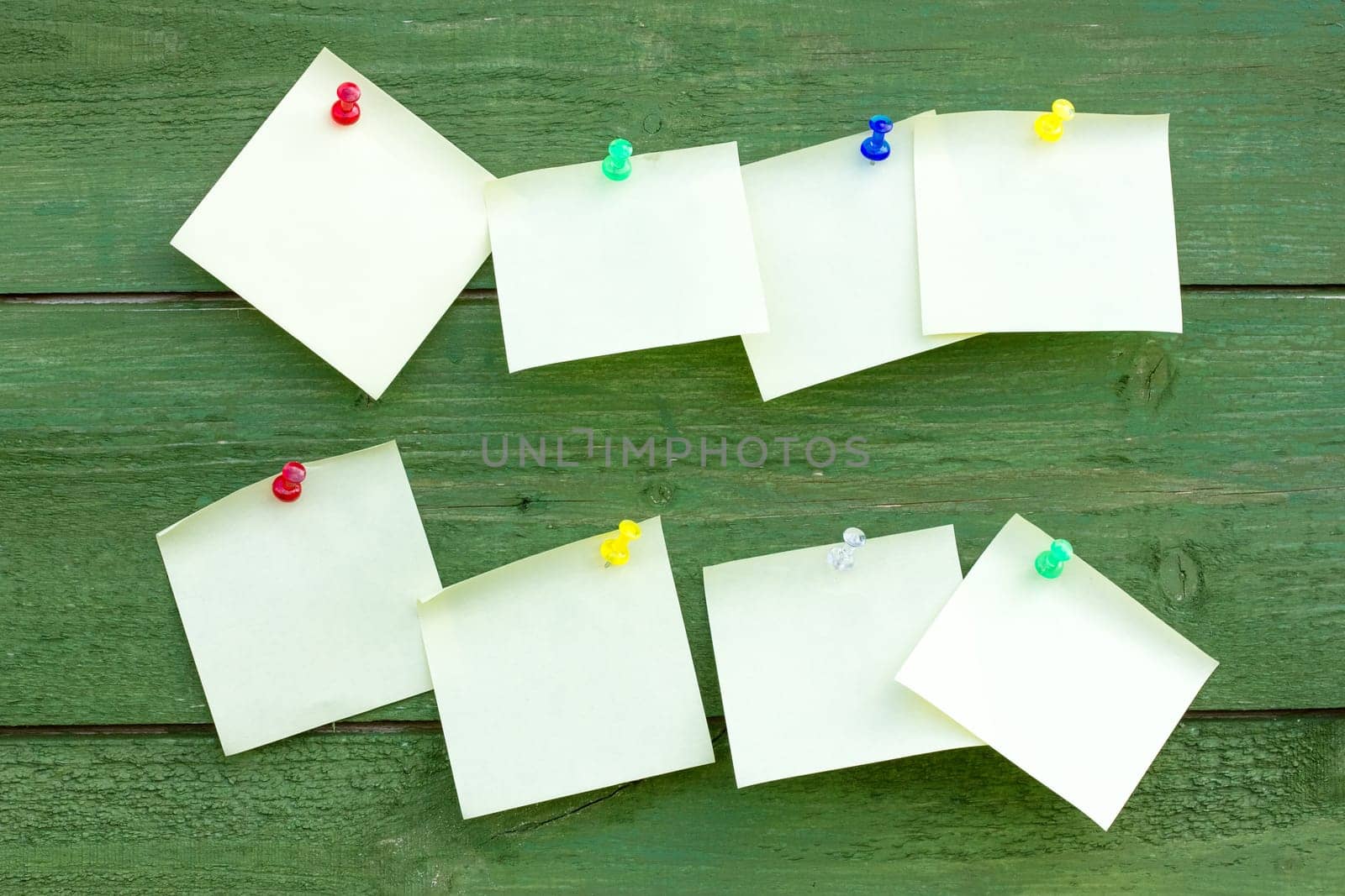 Green wooden wall with empty memo sticks
