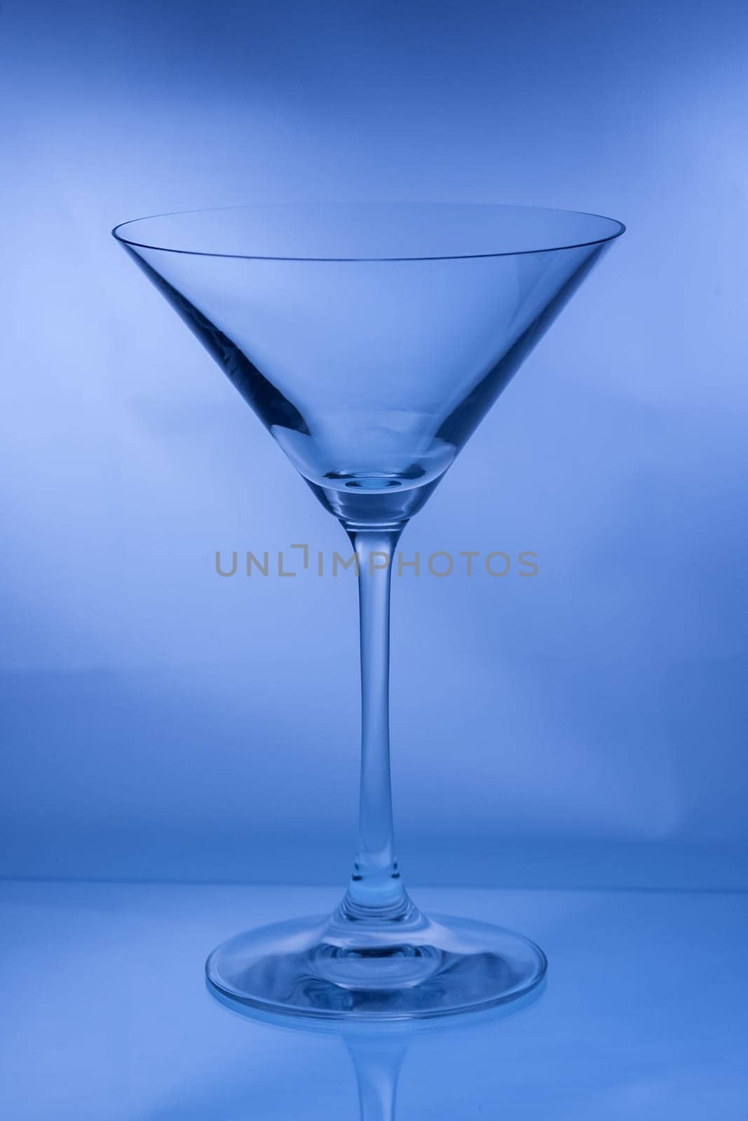 One empty martini glass in a vertical shot in blue tone light