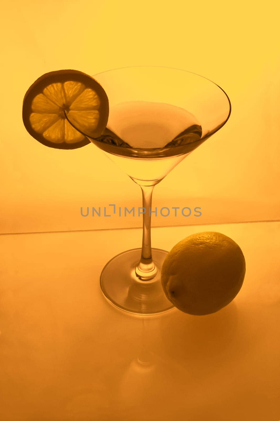 Martini glass with lemon slice and lemon from above in amber light