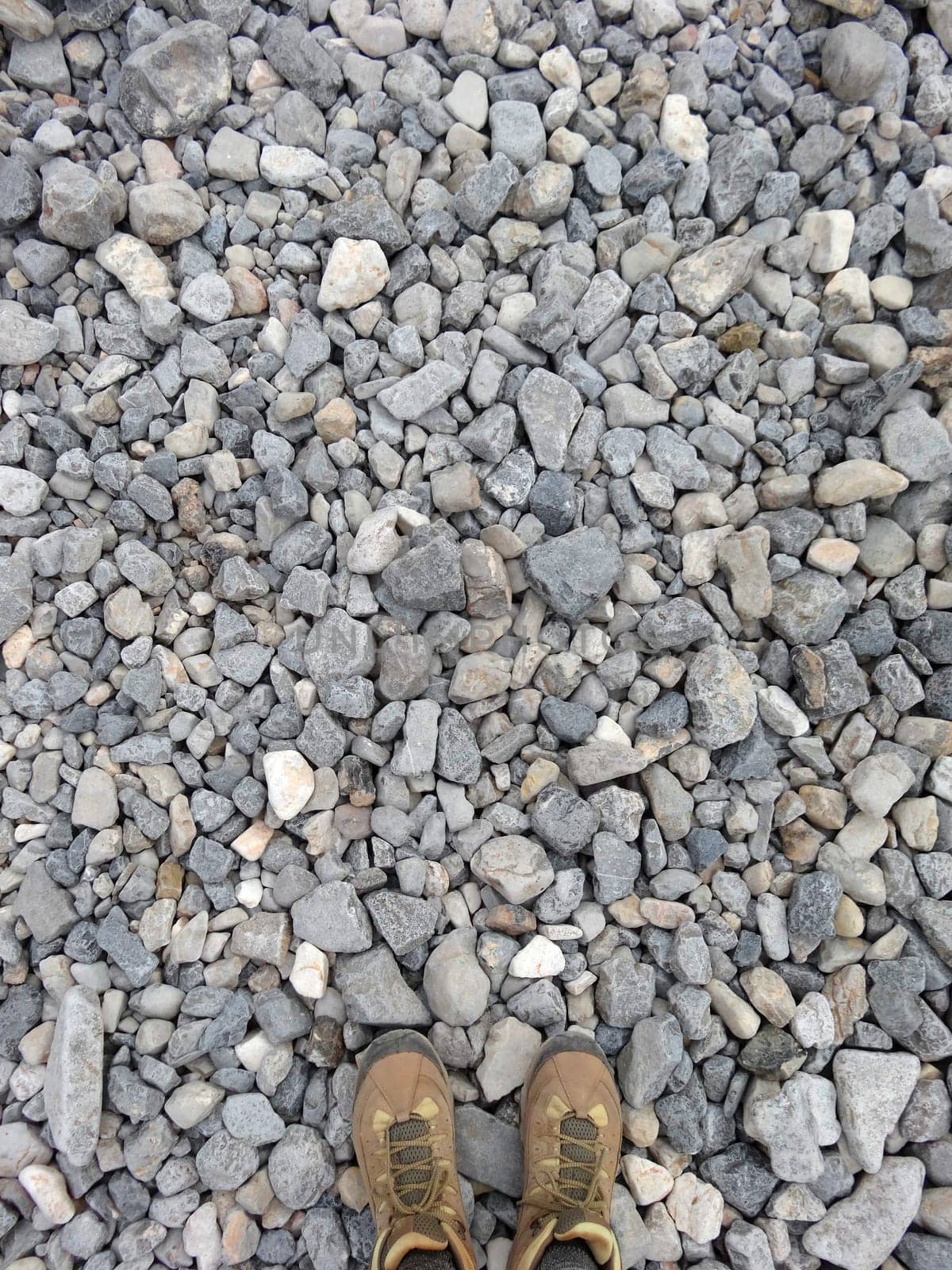 Vertical shot of a pair of hiking boots on gravel from above