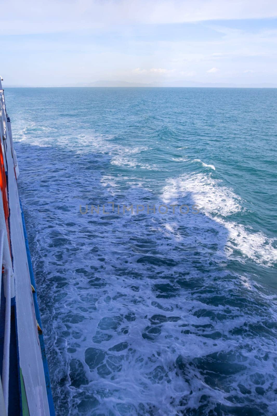 Vertical shot of waves and foam next to a moving ship