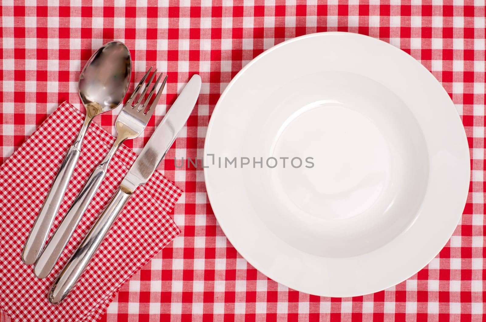 White plate and cutlery made of spoon,knife and fork with checkered napkin