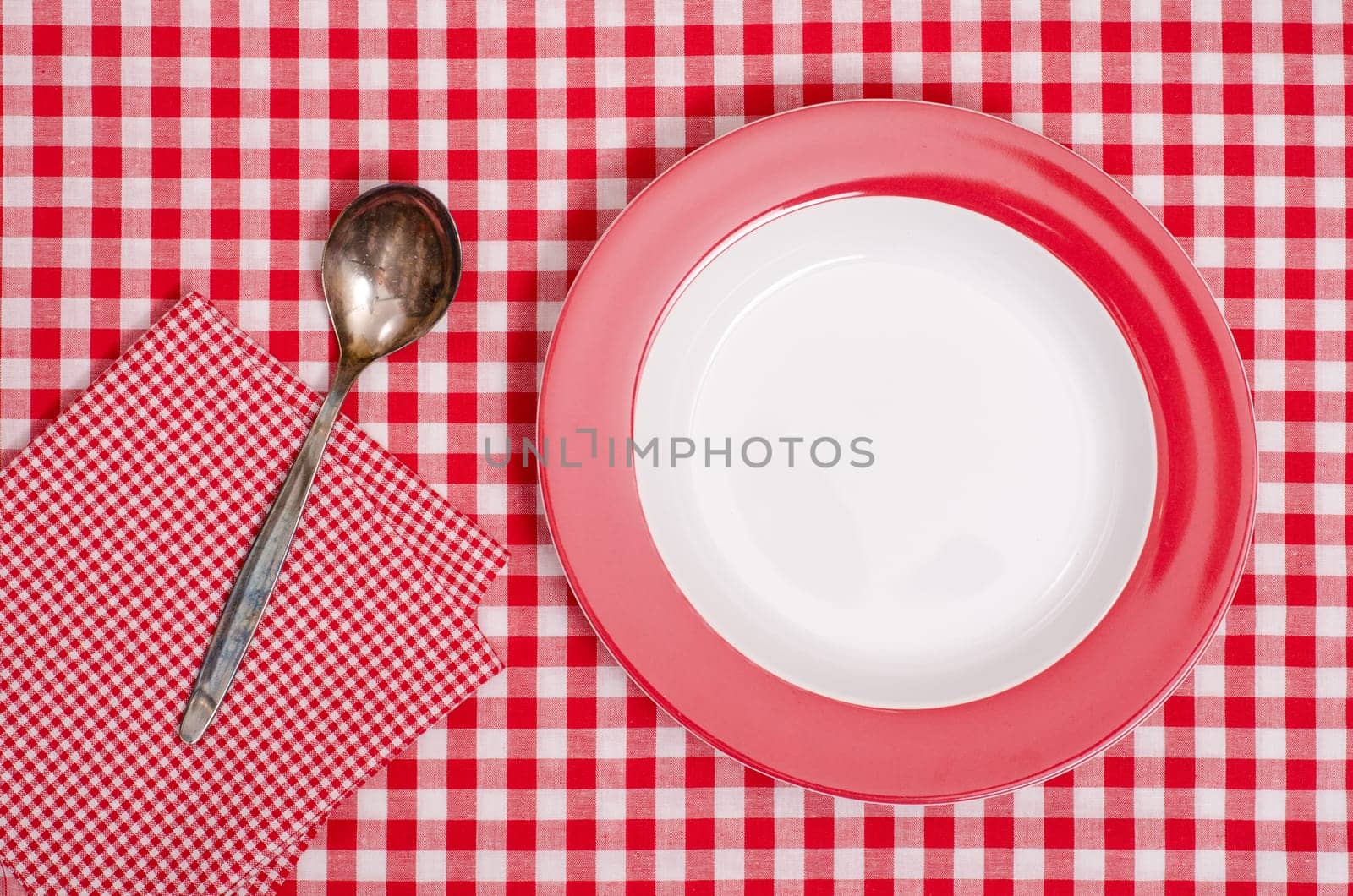 Empty tub with spoon and napkin on red and white checkered tablecloth