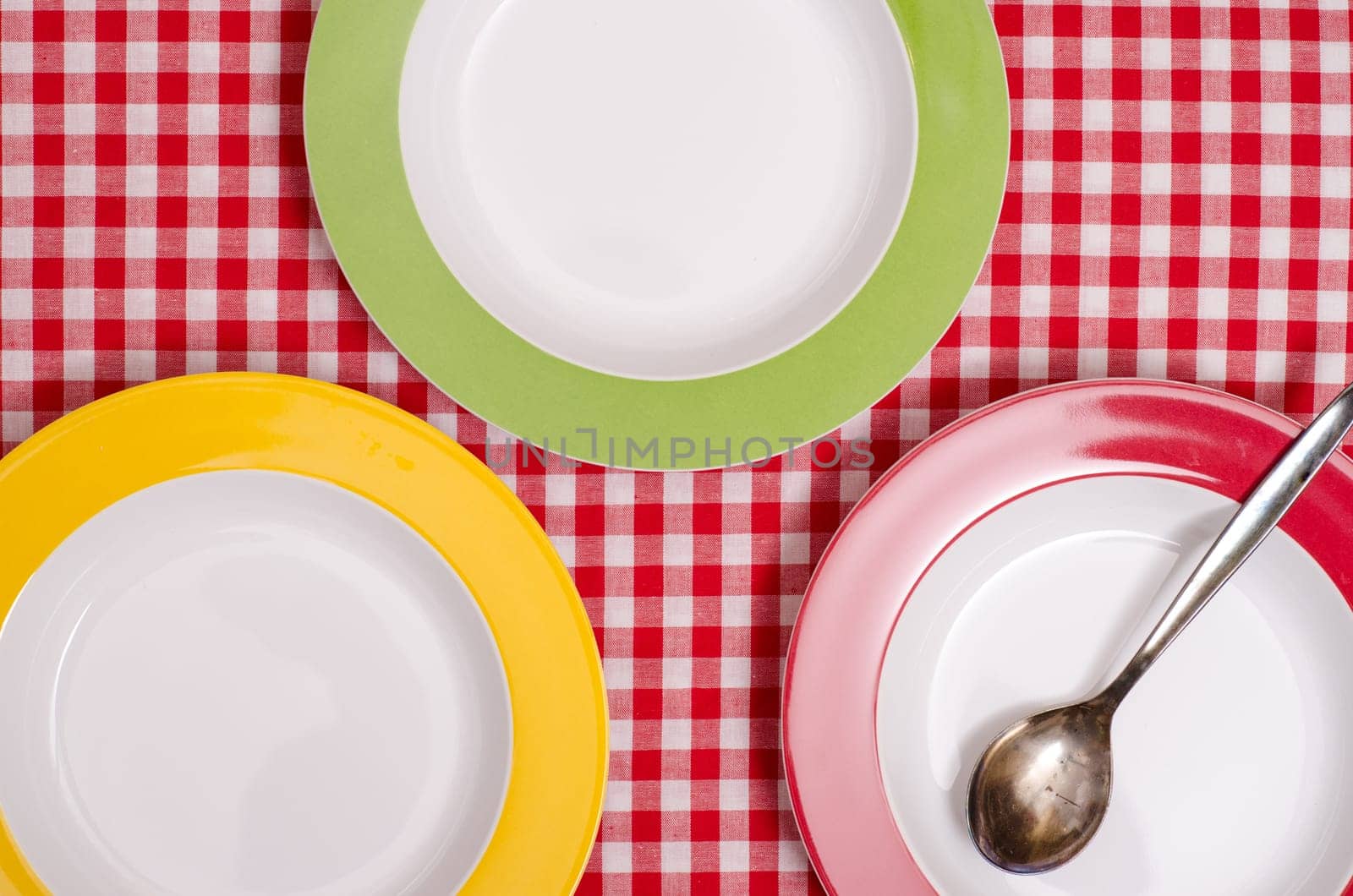 Three colorful plates and a spoon on checkered cloth