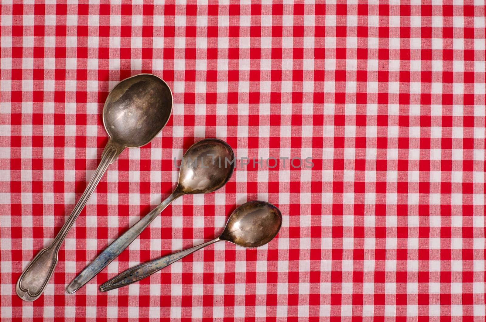 Three silver spoons on table with checkered cloth