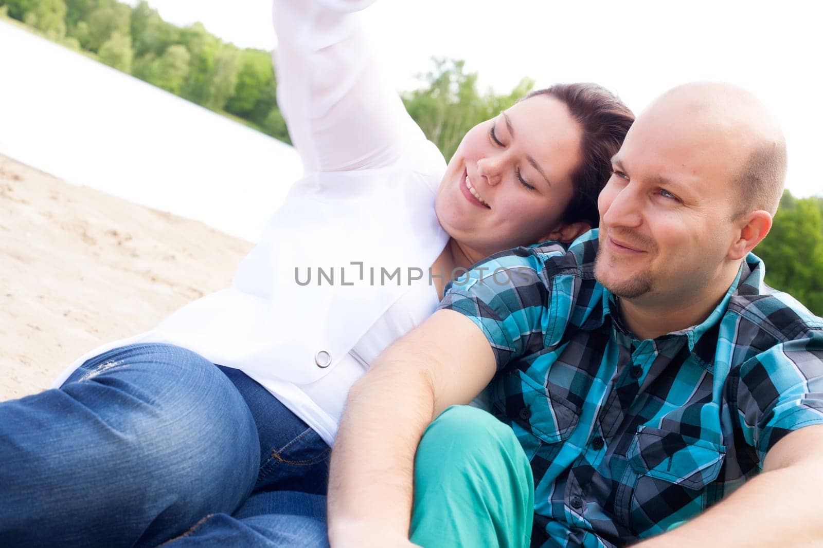 Happy young couple is having fun on a windy park beach