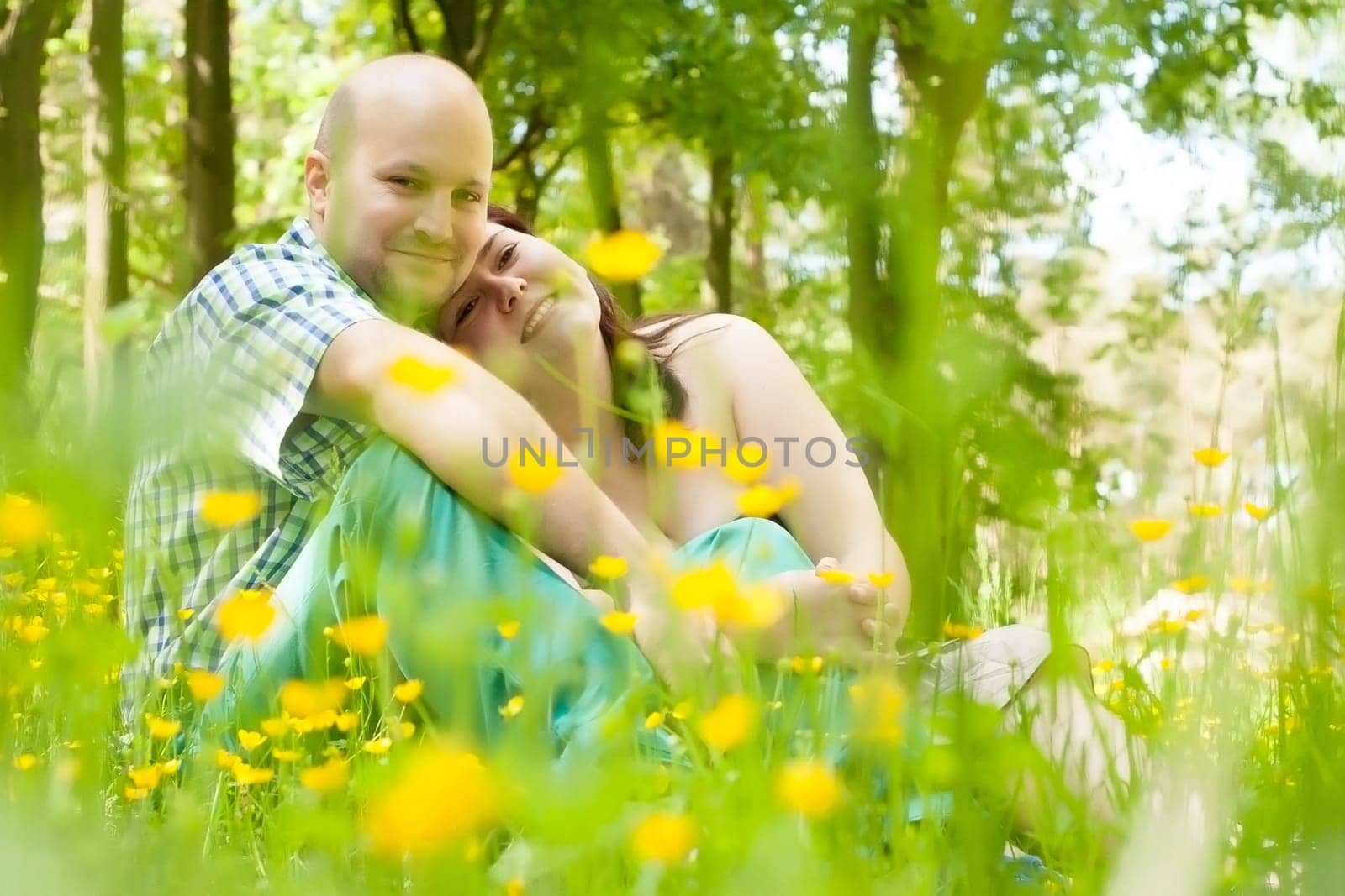 Happy young couple is sitting in a field of buttercups
