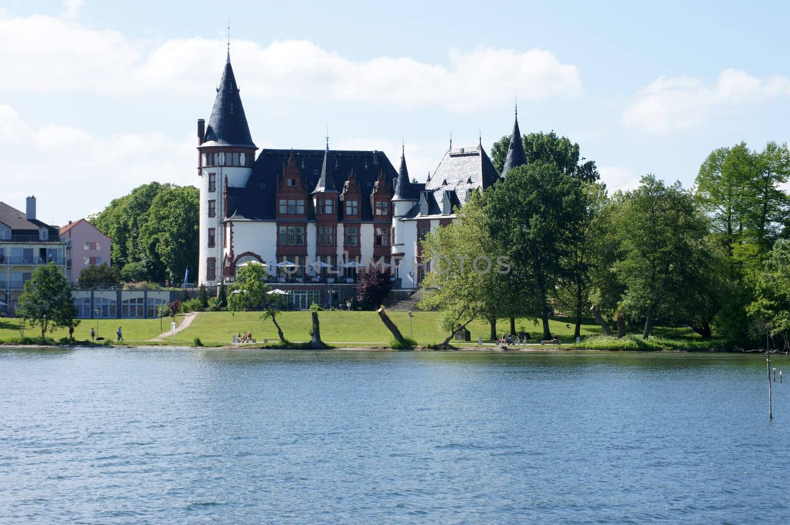 Waren, Mecklenburg Vorpommern/Deutschland  – Juni 09, 2013: Urlauber und Touristen gehen die Promenade des Schlosshotels Klink am 09. Juni 2013 in Waren entlang. Das Schloss ist ein bekanntes Hotel an dem See Mueritz.