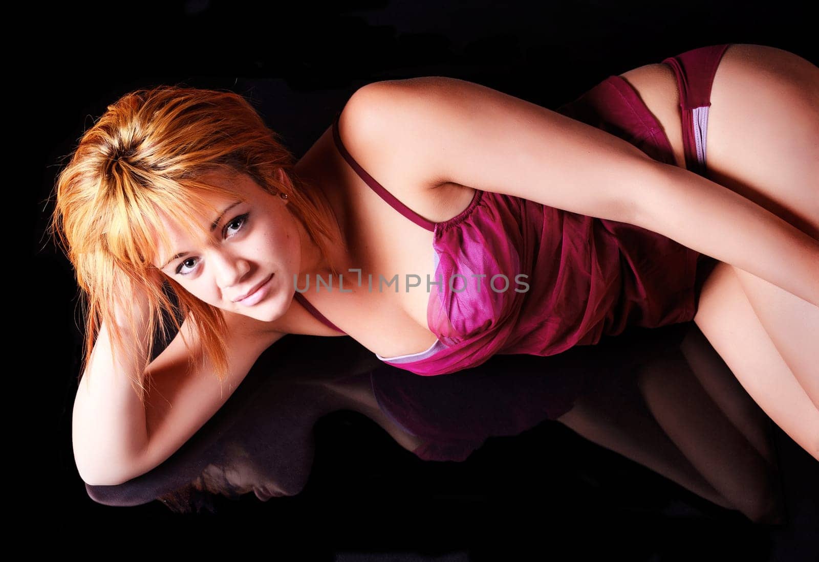 Sensual blonde girl in underwear lie and reflecting on dark background