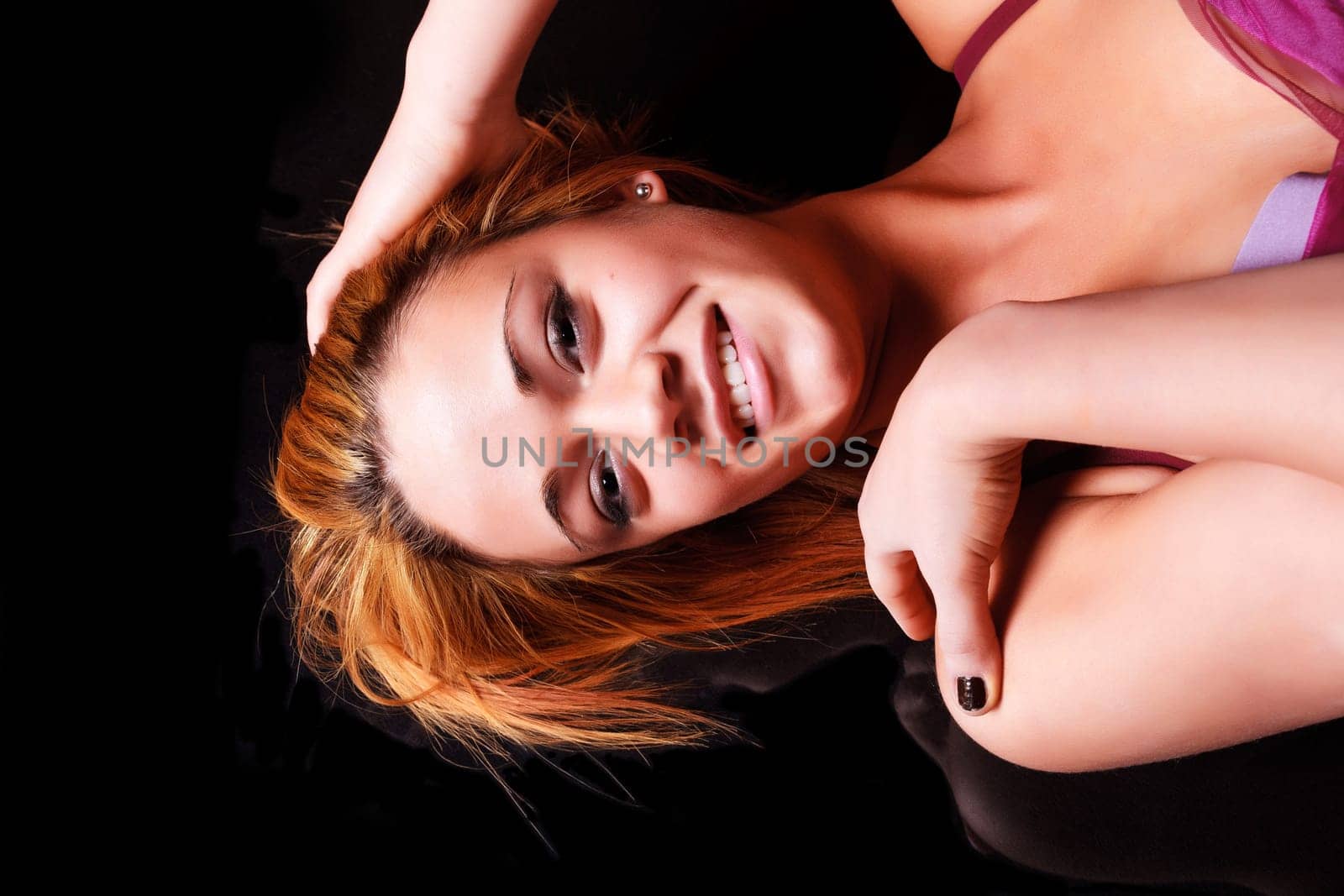 Sensual blonde girl in underwear lie and reflecting on dark background