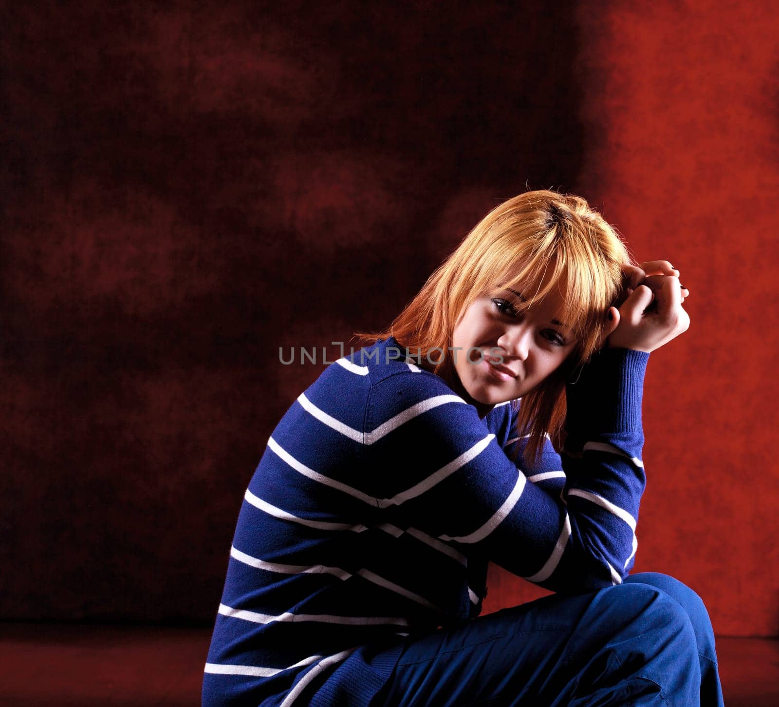 Girl sitting on the stool on red background