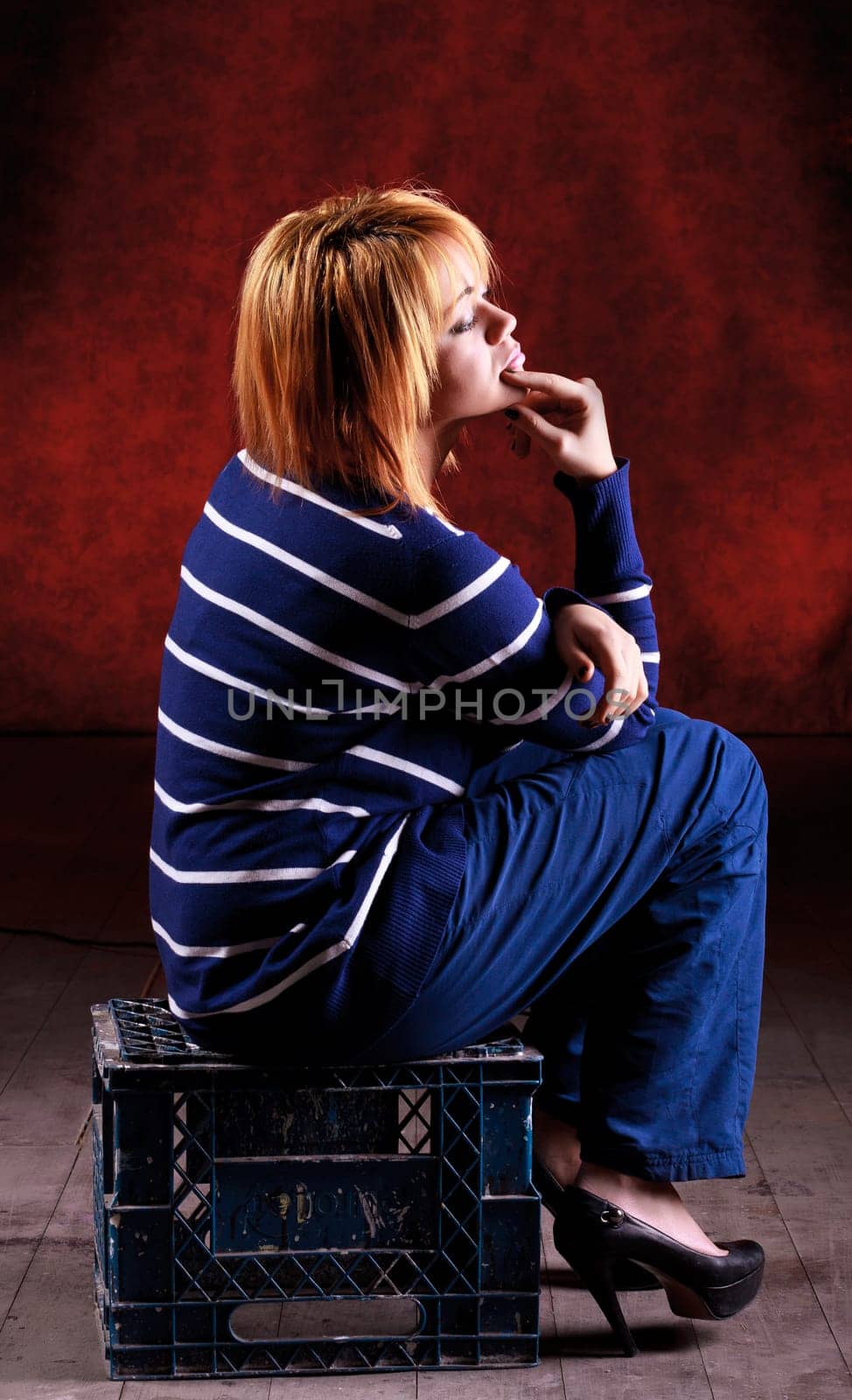 Girl sitting on the stool on red background