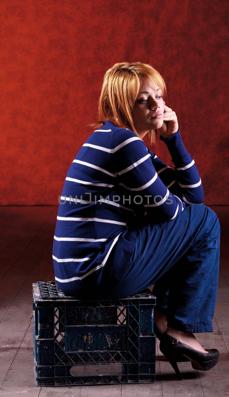 Girl sitting on the stool on red background