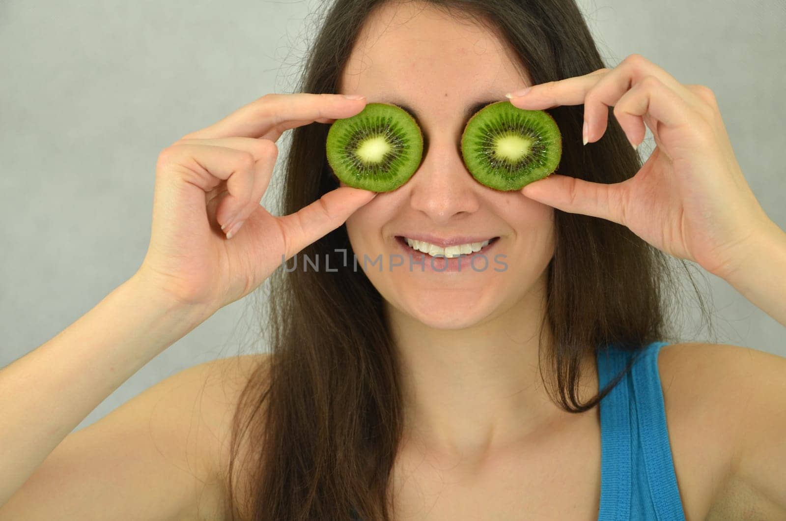 Beautiful young girl is holding kiwi fruit