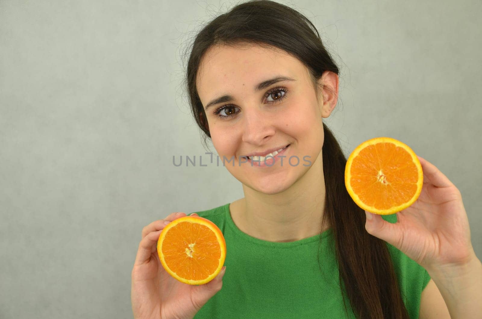 Beautiful young girl is holding an orange