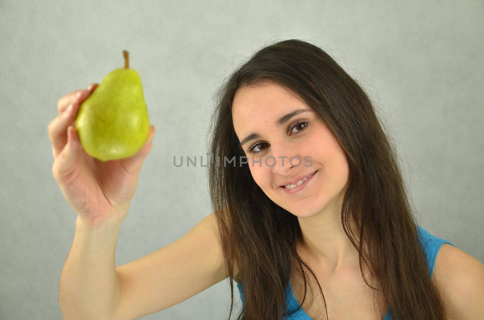 Beautiful young girl is holding a pear