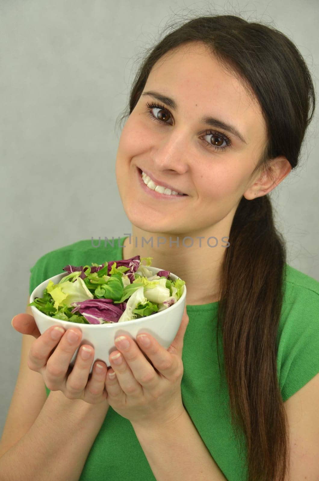 Beautiful young girl is holding an bowl of vegetables