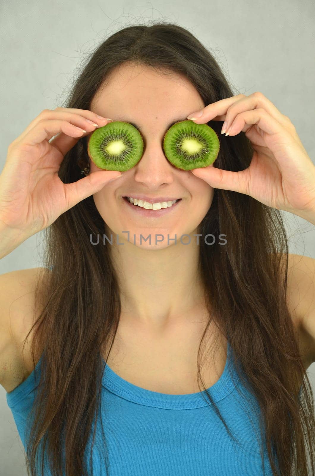 Beautiful young girl is holding kiwi fruit
