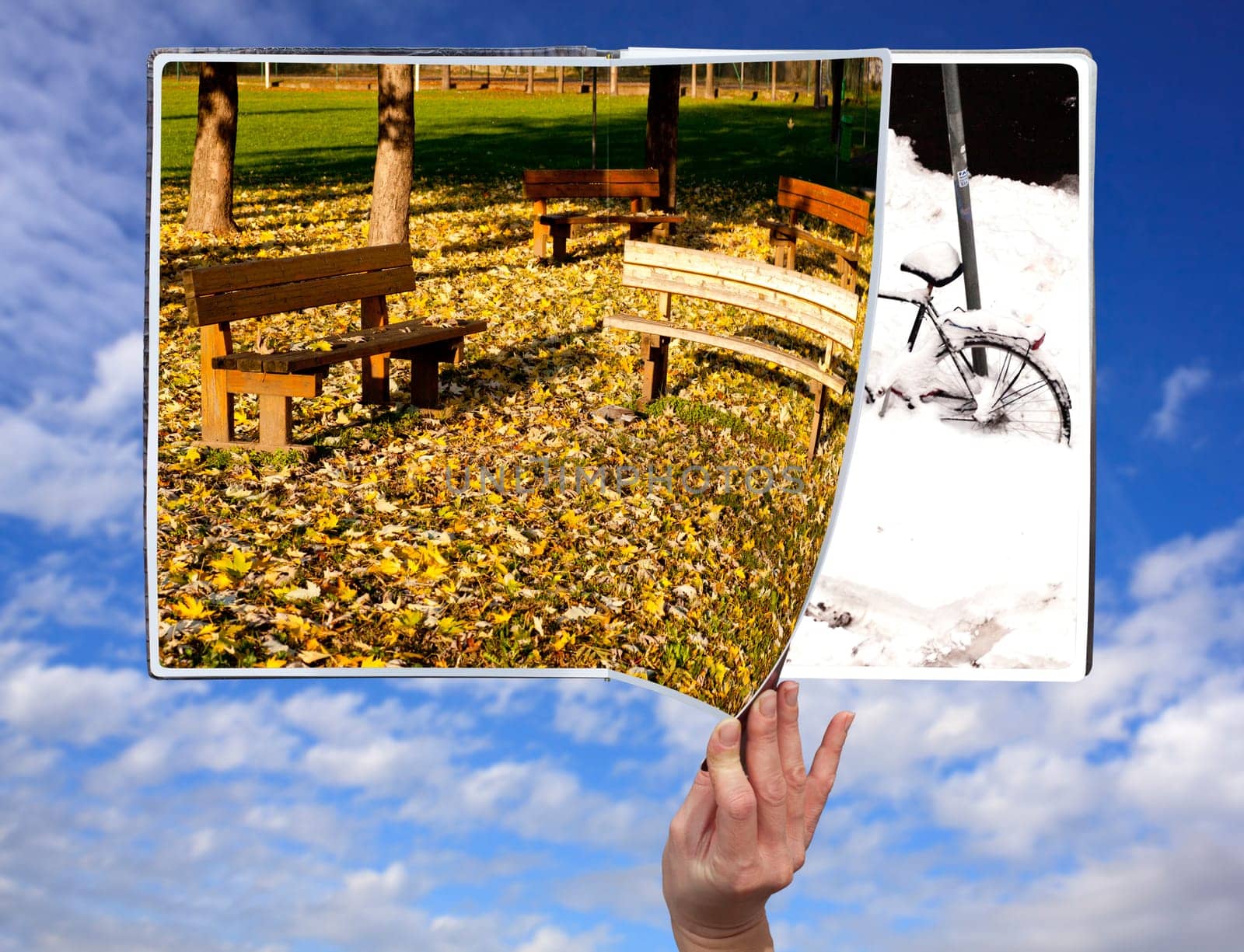 Hand through the book of seasons on cloudy sky