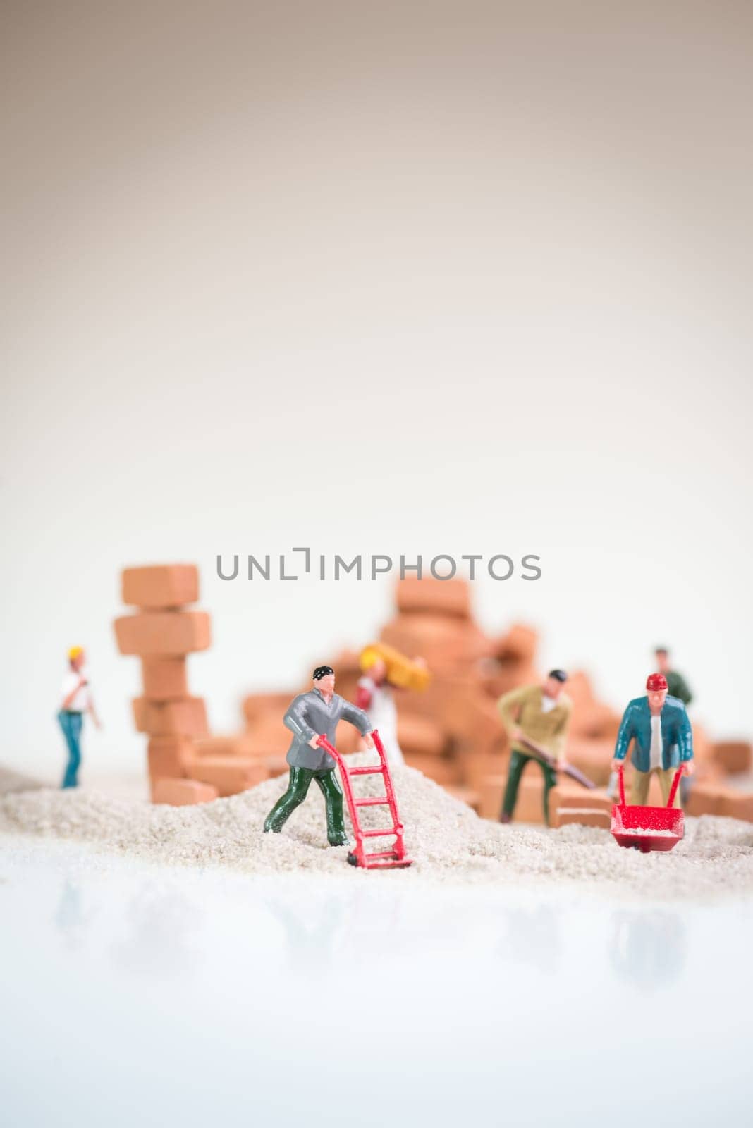 Miniature workmen doing construction work on a cloudy day with the overcast sky like background