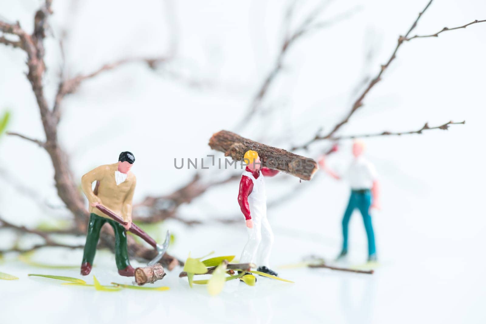 Miniature workmen busy in felling and cutting trees