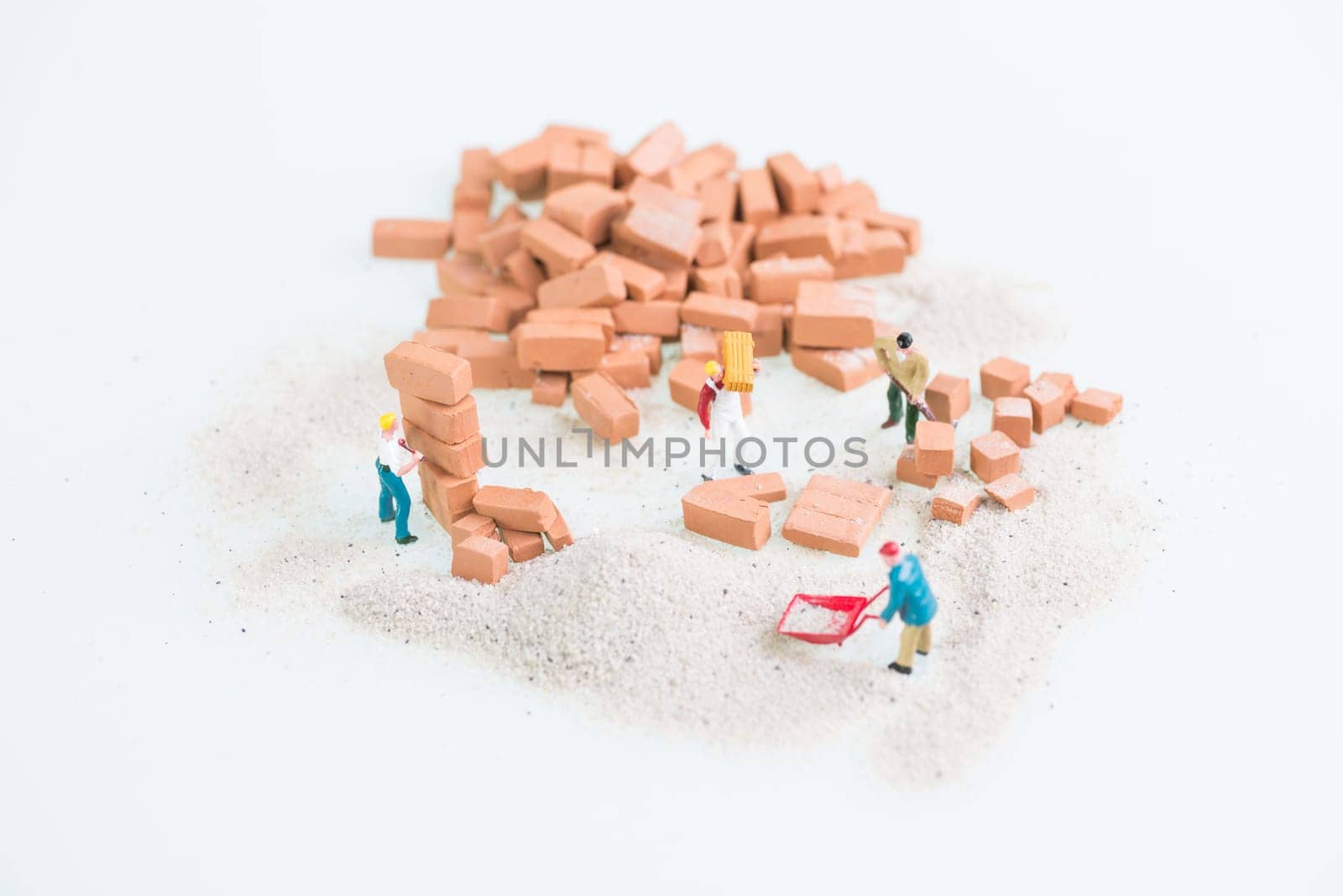 Miniature workmen doing brickwork top view close up