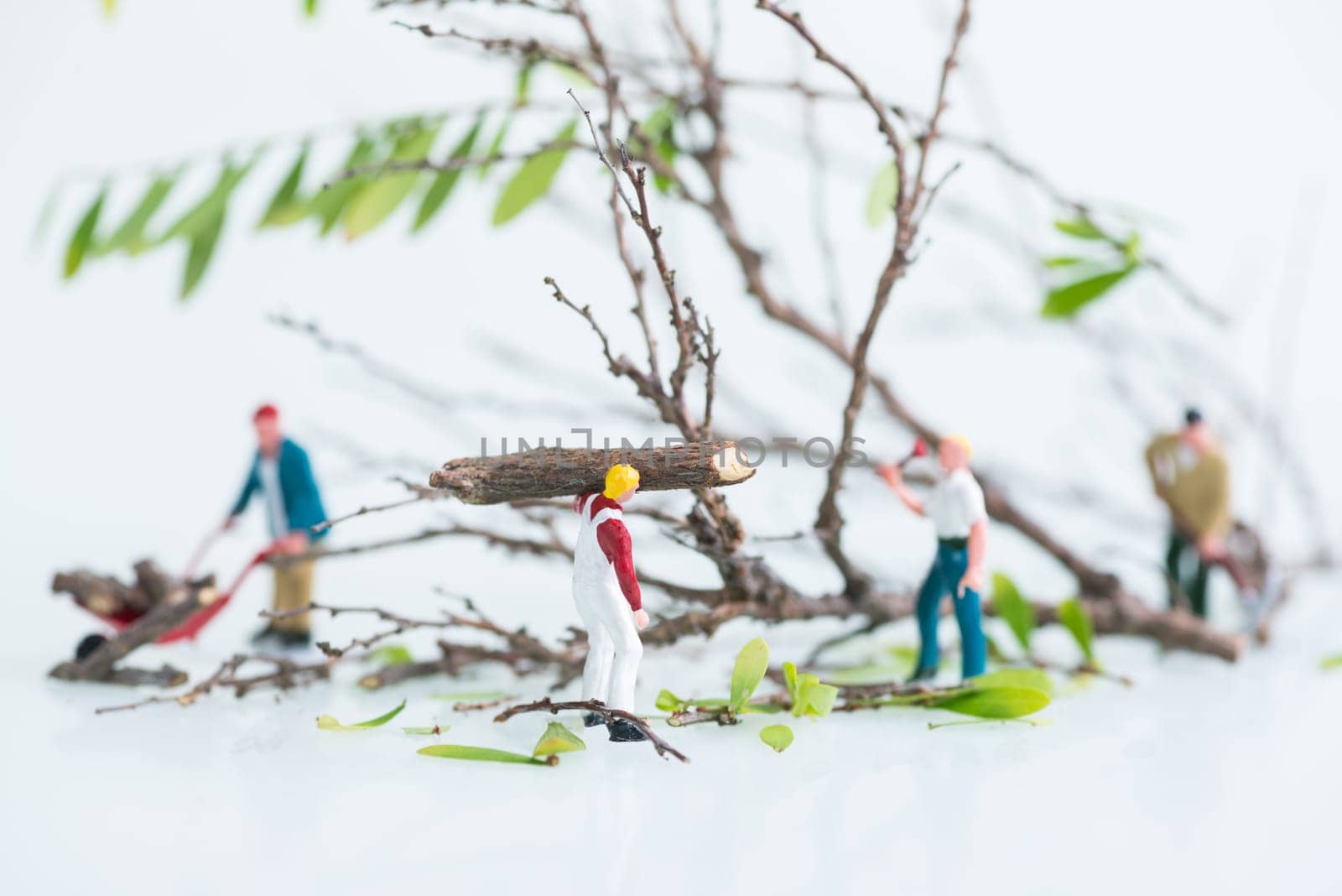Miniature workmen working together in felling and cutting trees close up