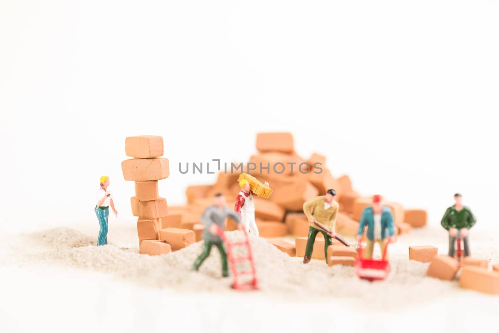 Miniature workmen working together in doing construction brickwork