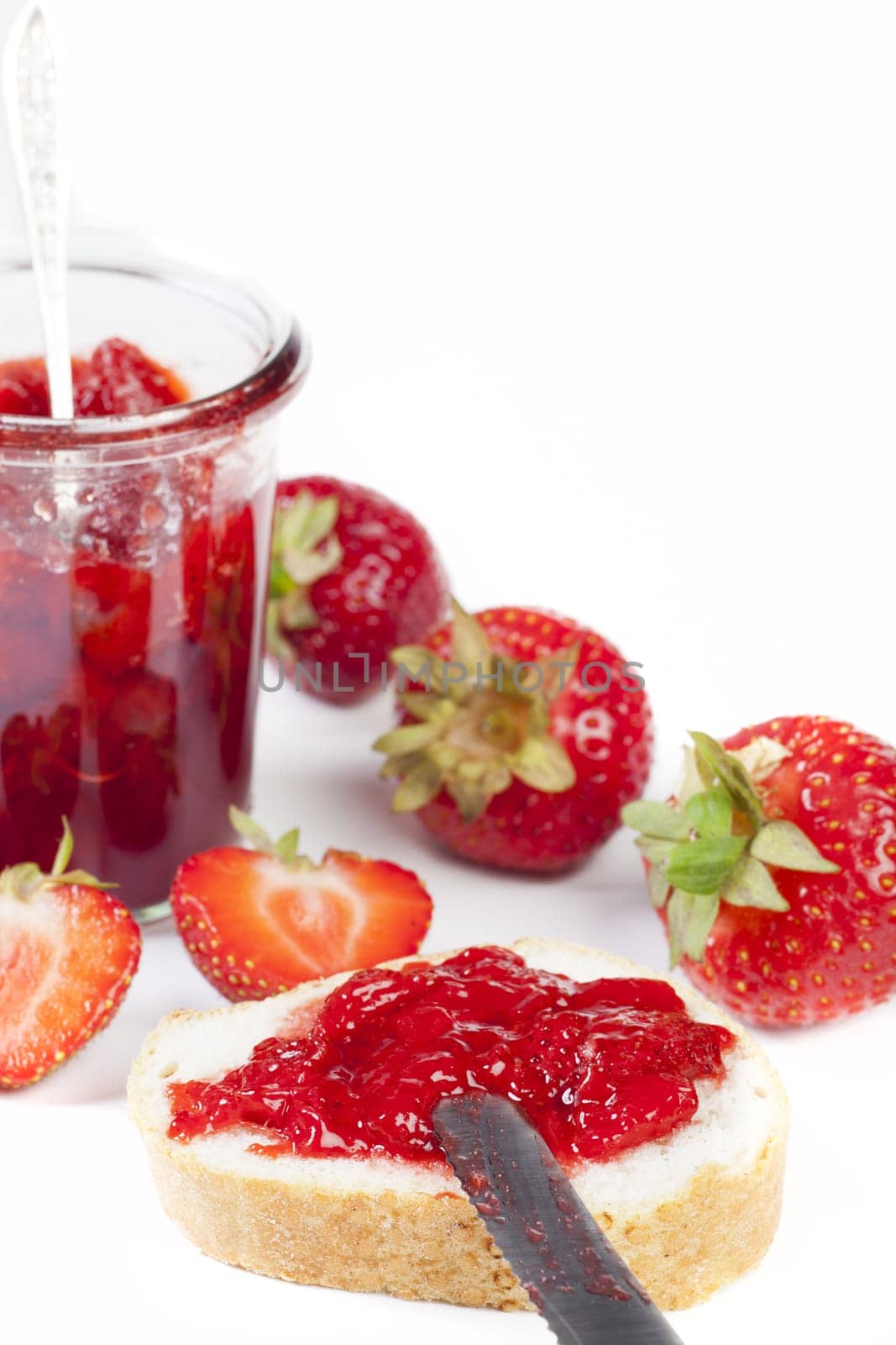 Homemade jam in a jar made from fresh strawberries on a white background