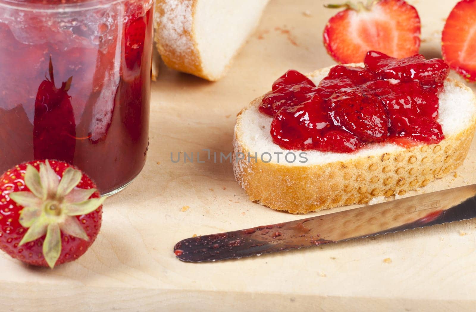 Fresh white bread with homemade strawberry jam on a wooden board
