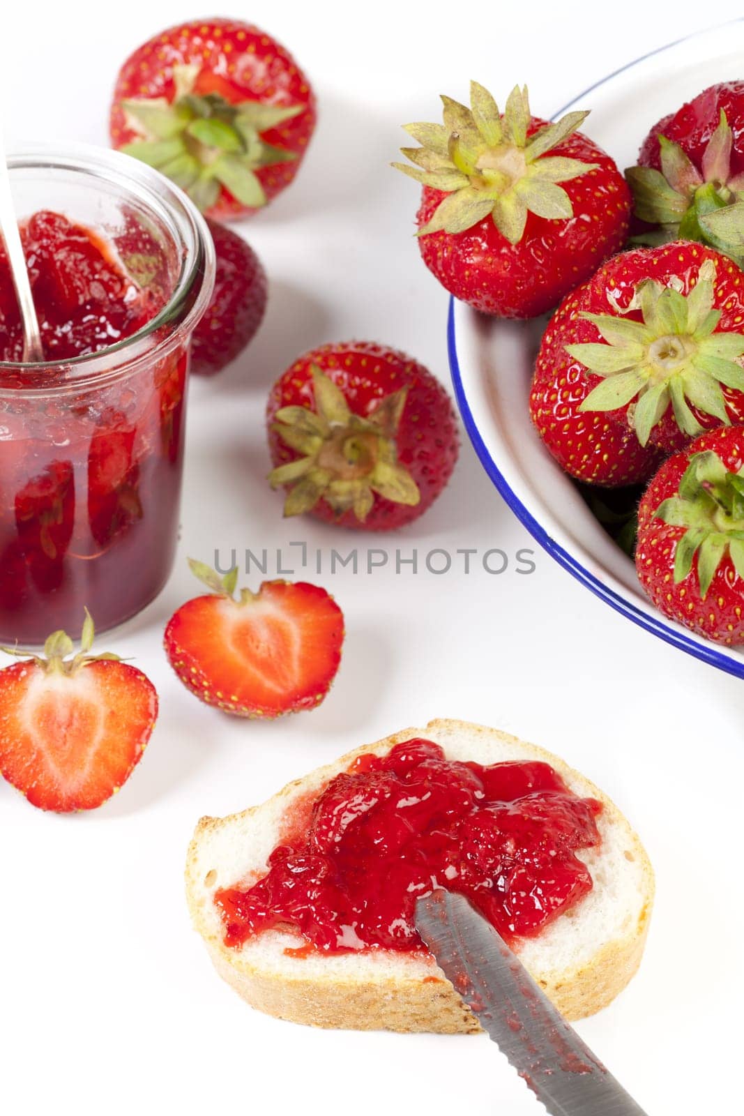 Homemade strawberry jam on white bread on a white background