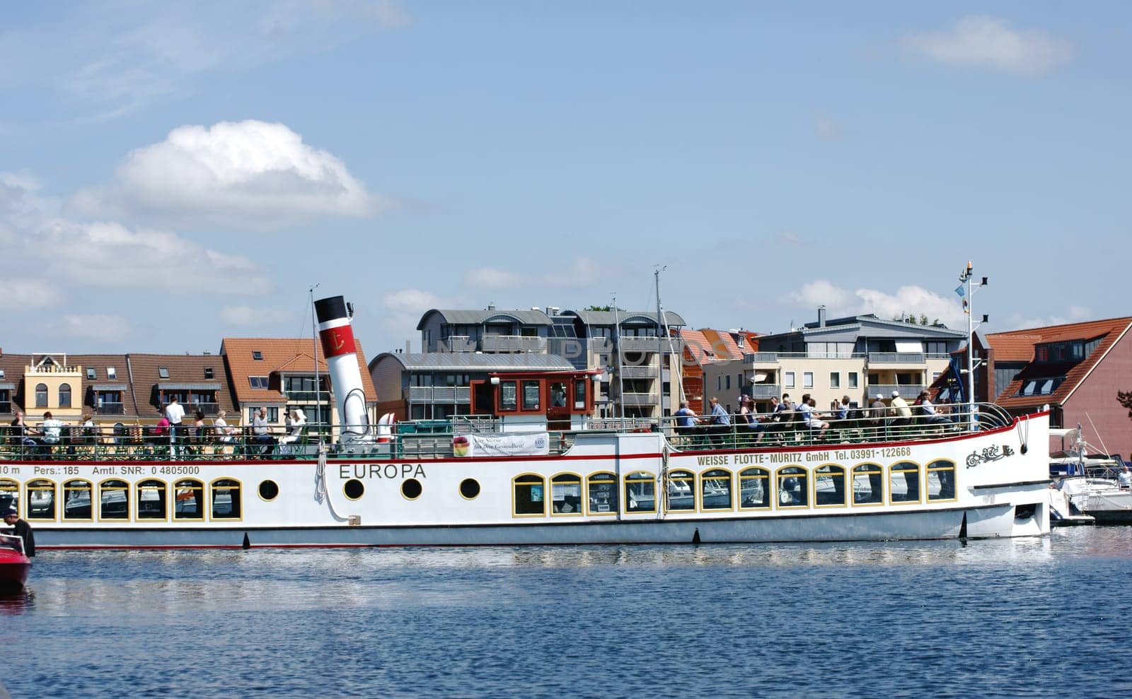Waren,Mecklenburg Vorpommern/Germany – June 09,2013: The entrance of the excursion steamer Europa into a port of the Mueritz with unknown persons sitting on the roof terrace on June 9th in Waren.
