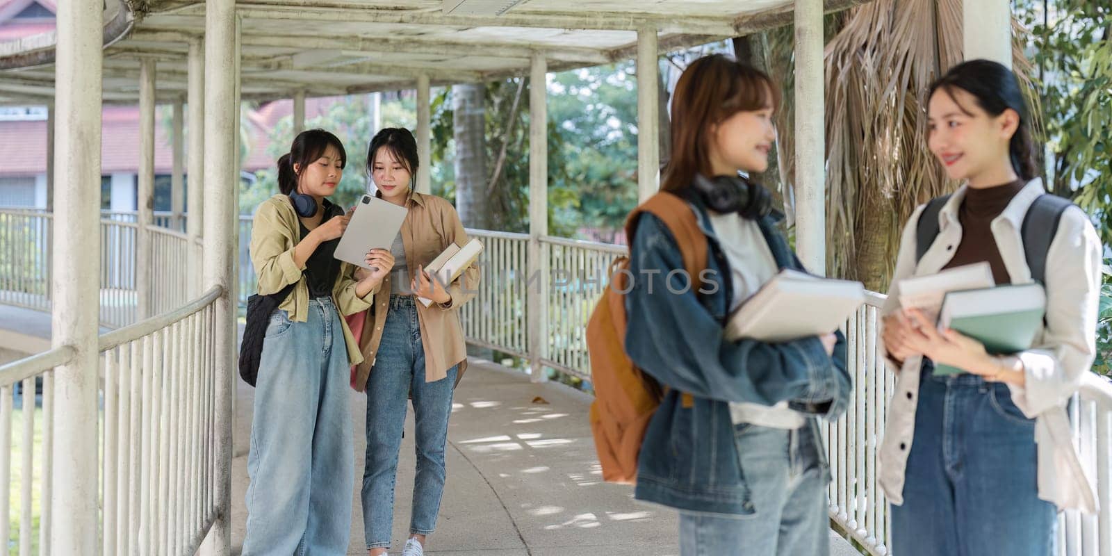 university students using a digital tablet while walking to next class by itchaznong