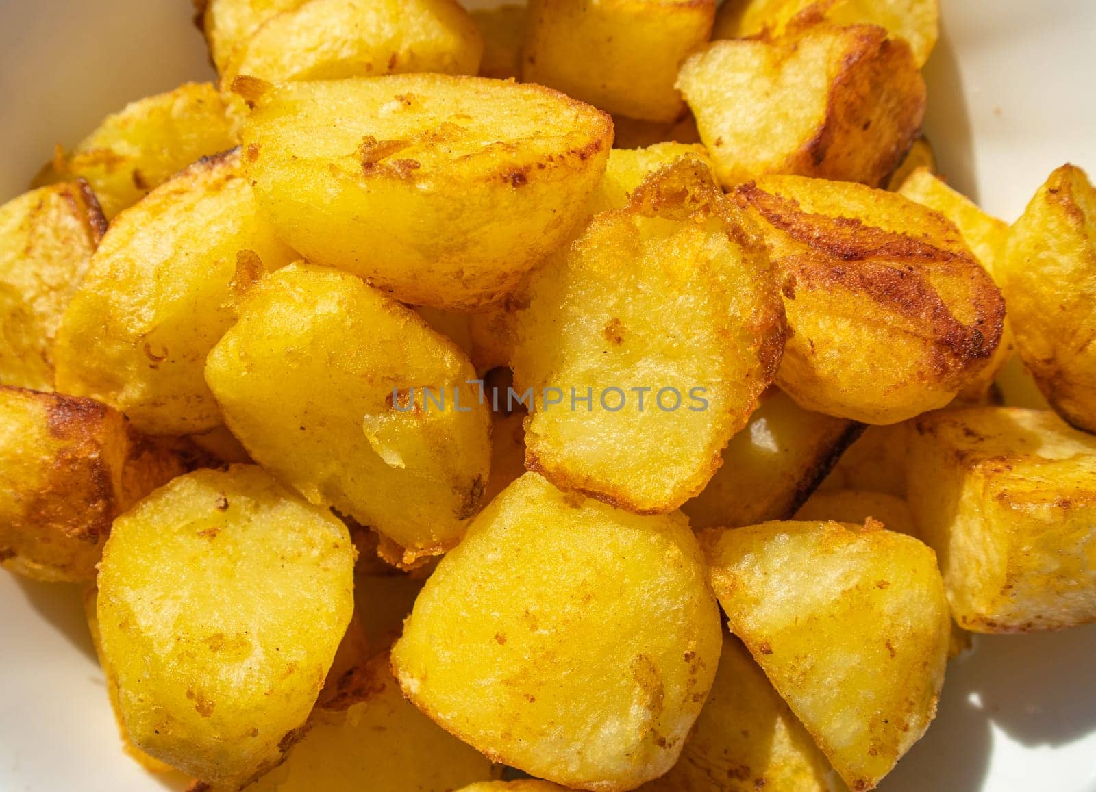 Potatoes fried in a frying pan close-up, lying on a white plate, Horizontal view from above, food background by claire_lucia