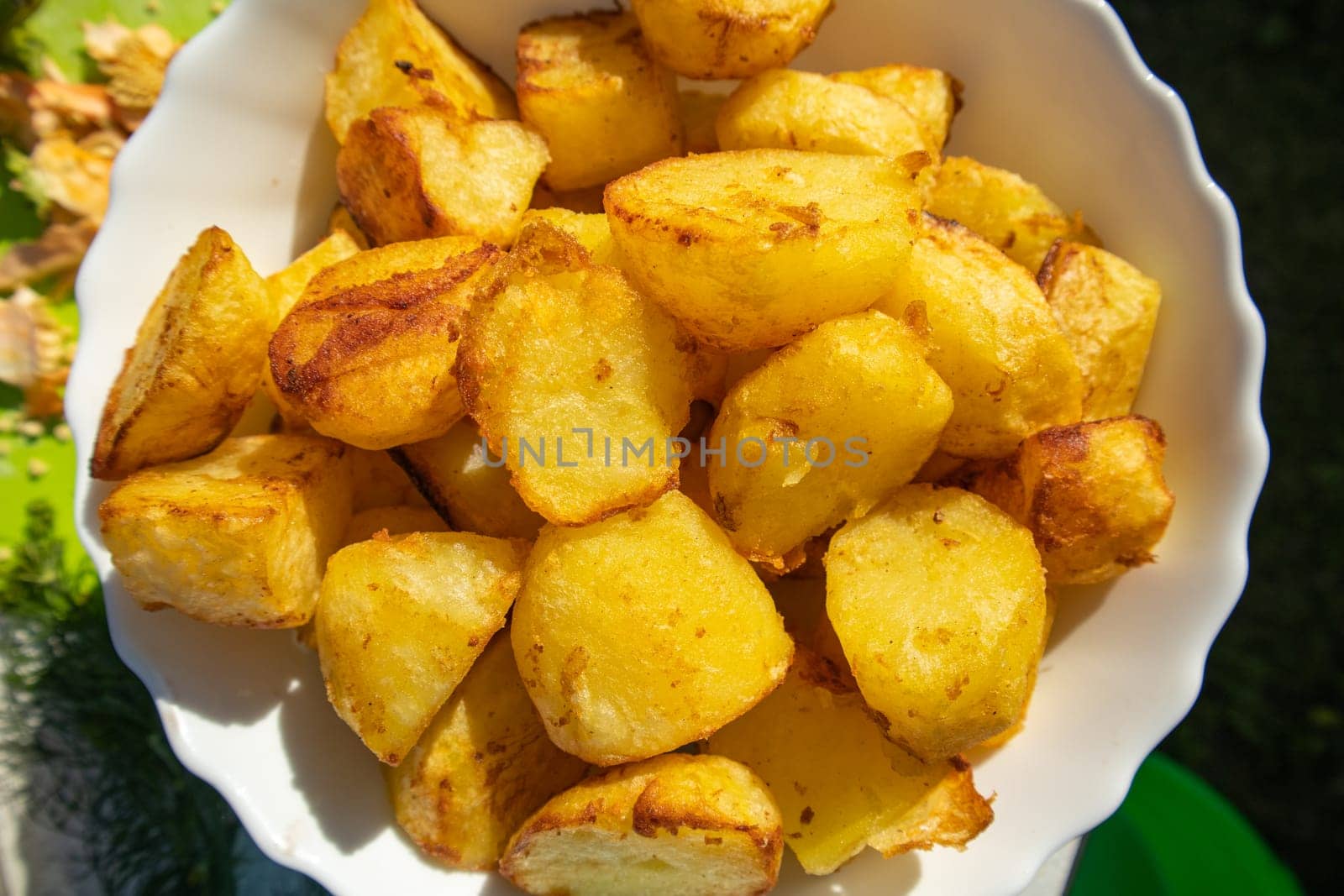 Potatoes fried in a frying pan close-up, lying on a white plate, Horizontal view from above, food background.