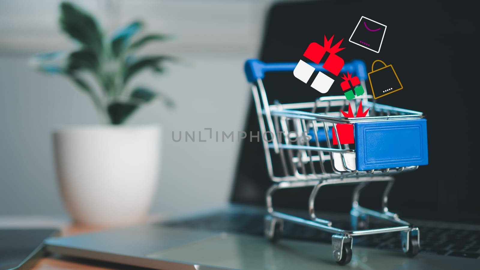 Shopping cart and gift box icons placed on laptop computer represent online shopping concept, website, market platform, technology, e-commerce, shipping, logistics and online payment concept. by Unimages2527