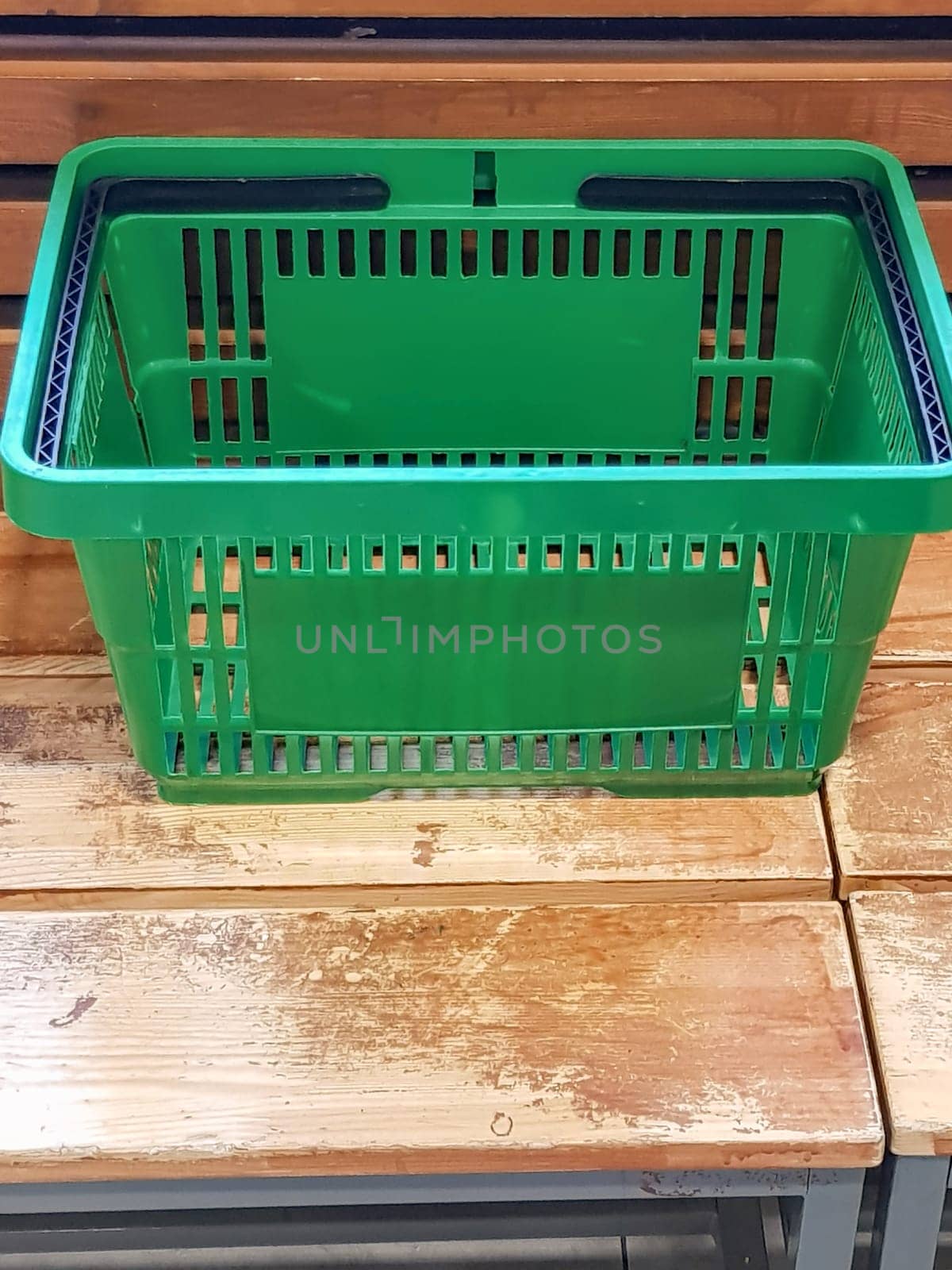 An empty green plastic shopping basket stands on the packing table, close-up, space for text at the bottom by claire_lucia