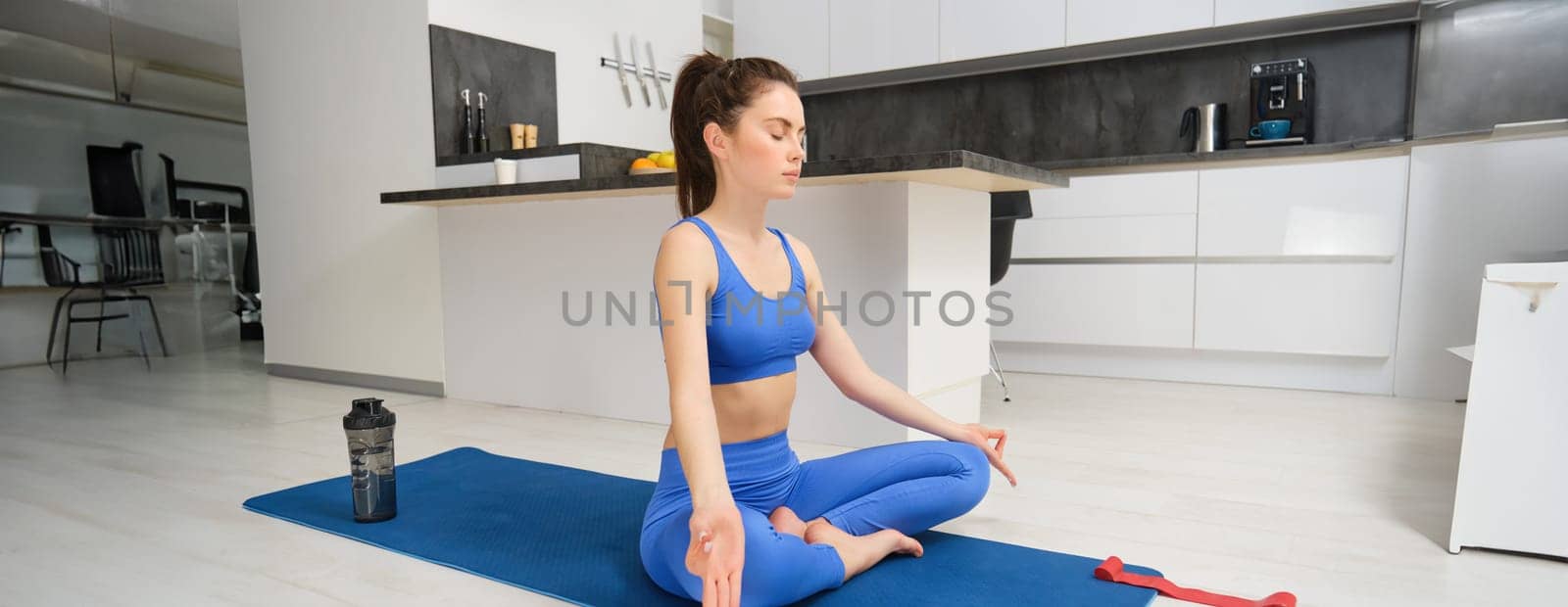 Image of beautiful woman doing training, workout from home in living room, practice yoga, sitting on floor and meditating.