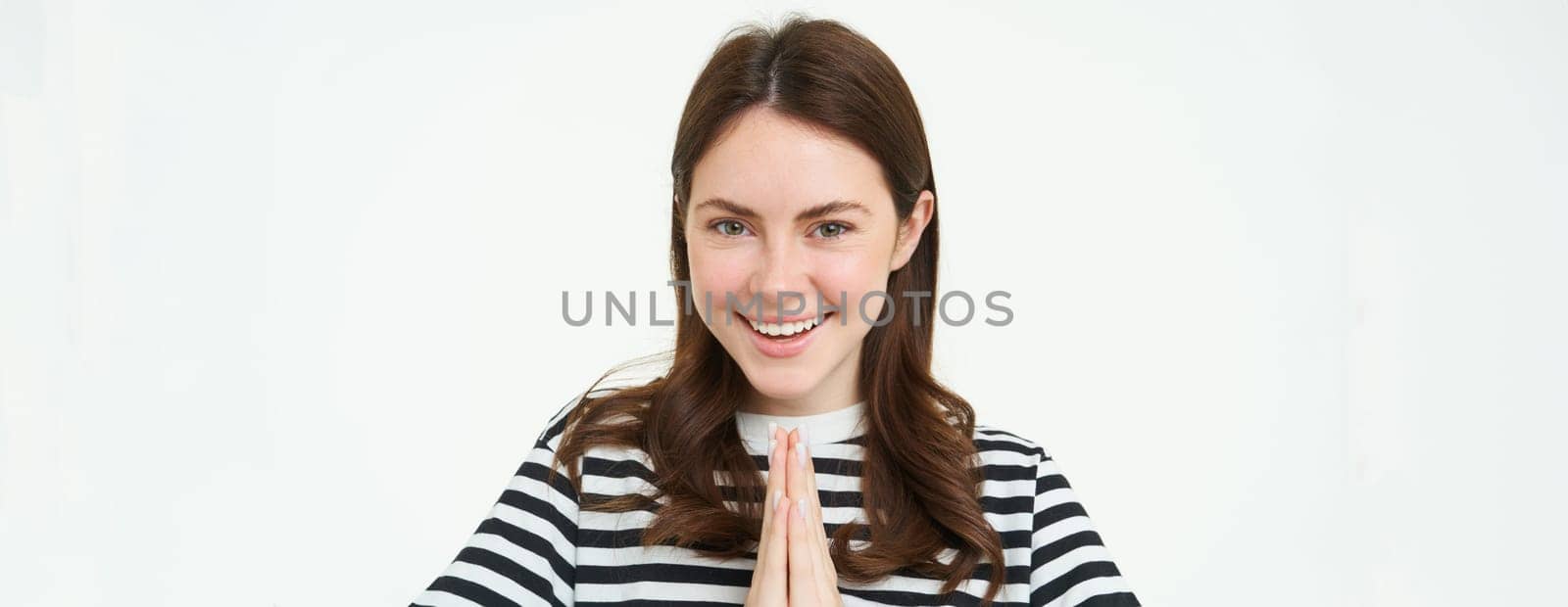 Portrait of woman showing namaste gesture, holding palms clenched together near chest, standing isolated over white background by Benzoix