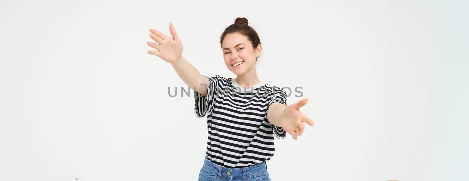 Portrait of cute smiling woman stretches her hands, reaches to hold something, wants to hug you, standing over white background by Benzoix