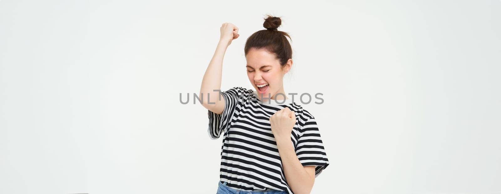 Portrait of happy woman winning, celebrating victory, rooting for team, triumphing, standing over white background.