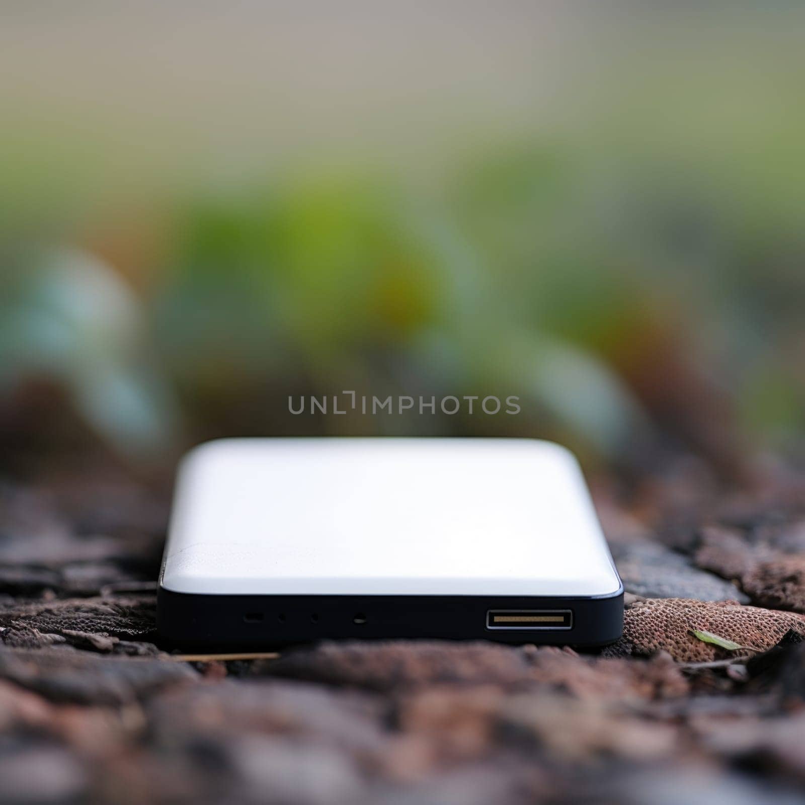 A white and black device is sitting on a leafy ground