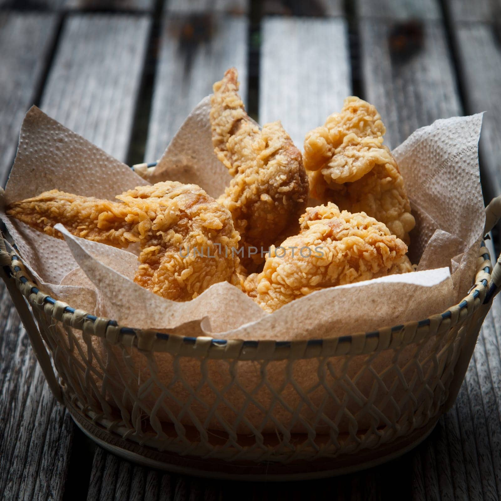 Fried Chicken in a basket on a wooden floor.