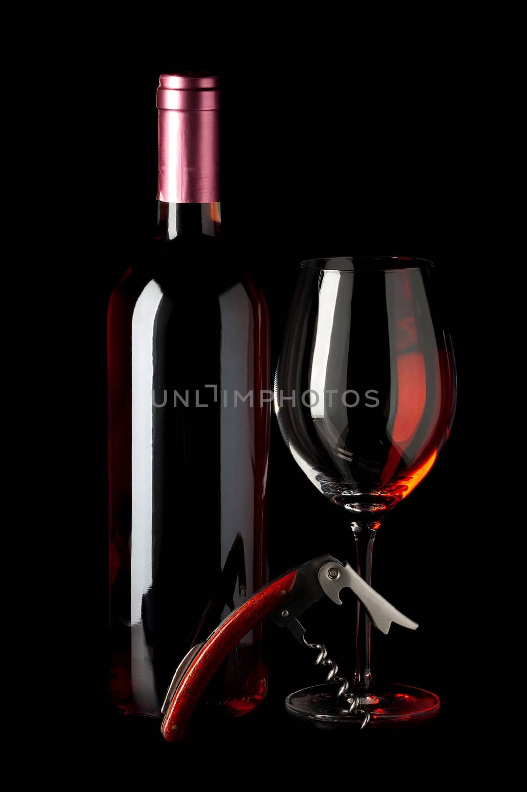 Bottle of red wine,a corkscrew and a wine glass insulated against a black background