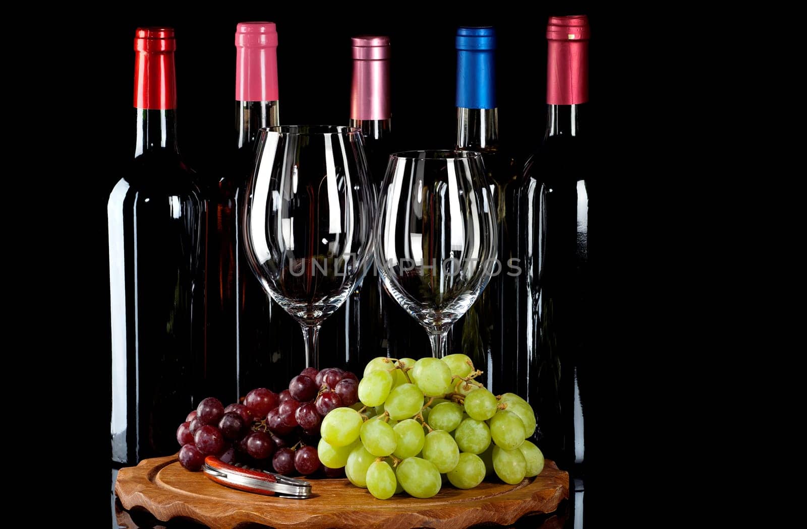 Wine bottles,wine glasses and grapes on a wooden board insulated on a black background