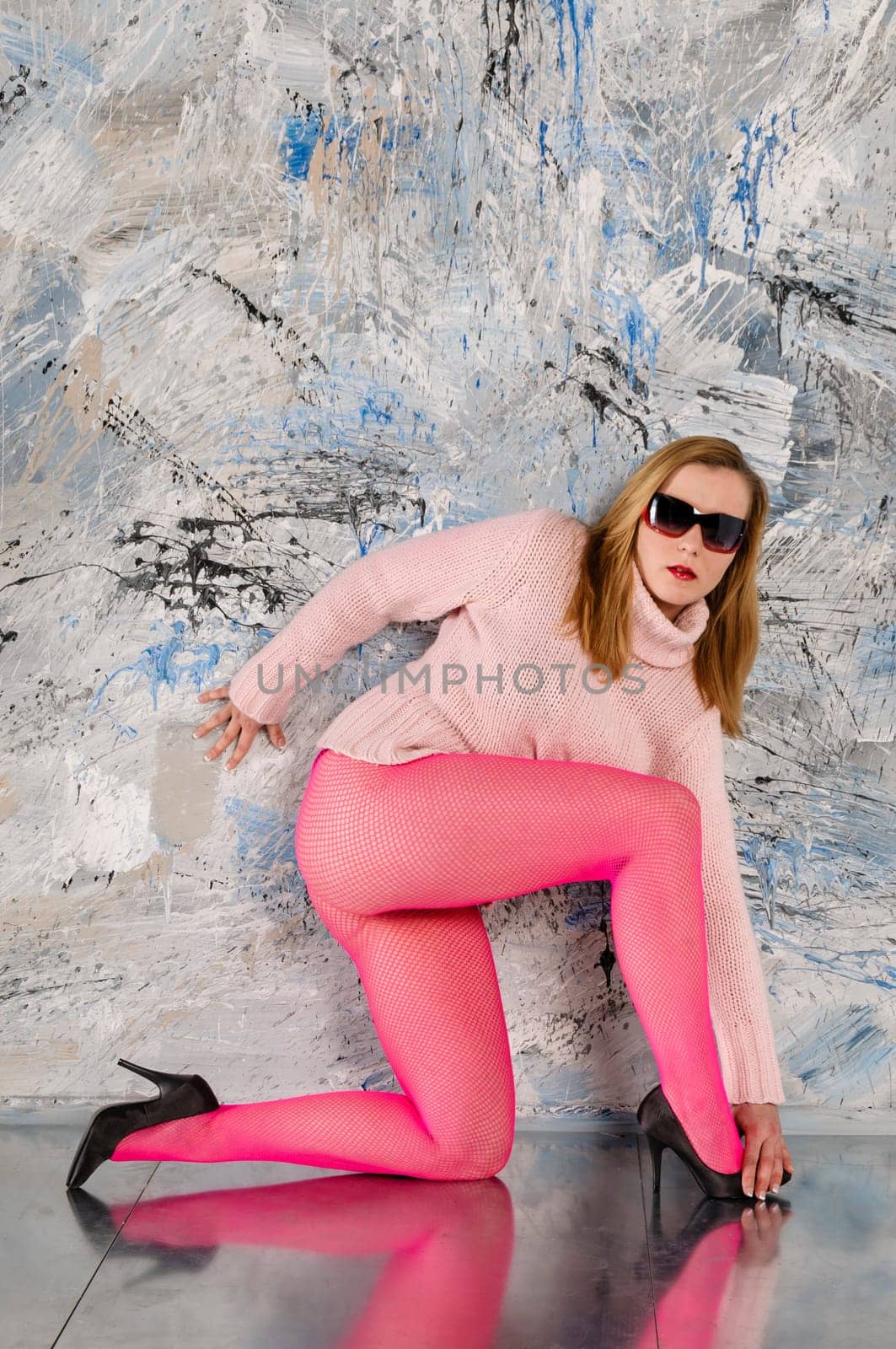 Sexy blonde poses in pink tights on a metal floor.